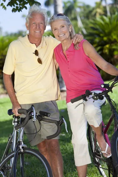 Šťastný starší pár na kolech v zeleném parku — Stock fotografie