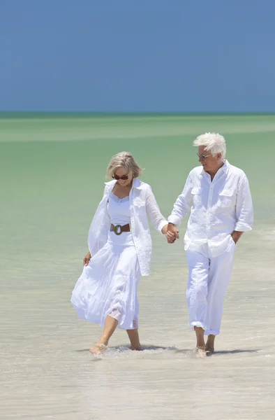 Šťastný starší pár chůzi držení rukou na tropické pláži — Stock fotografie