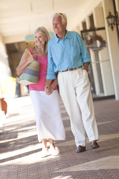 Feliz pareja de ancianos sosteniendo las manos en el centro comercial — Foto de Stock