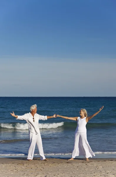Feliz pareja mayor bailando sosteniendo las manos en una playa tropical — Foto de Stock