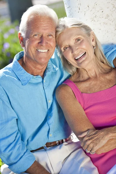 Feliz pareja de ancianos sonriendo afuera bajo el sol — Foto de Stock