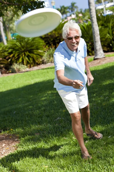 Glücklicher Senior wirft Frisbee bei Sonnenschein nach draußen — Stockfoto
