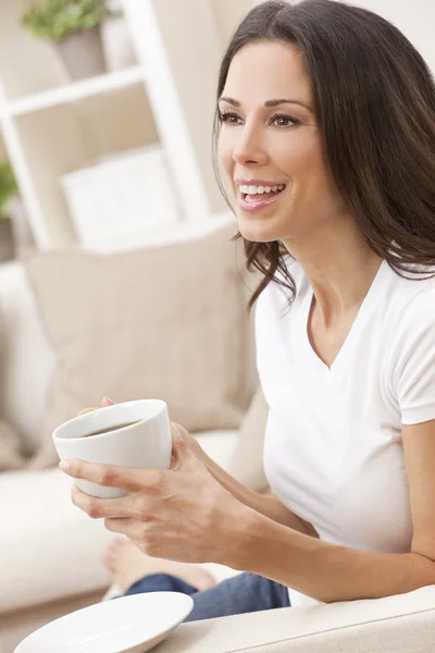 Glückliche Frau sitzt auf dem Sofa und trinkt Tee oder Kaffee — Stockfoto
