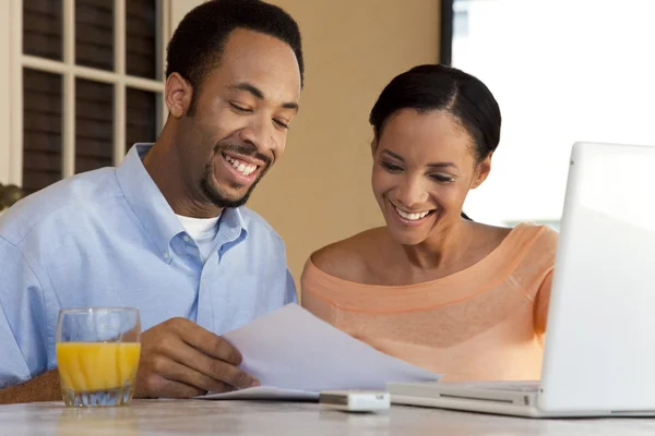 Ευτυχισμένο ζευγάρι αφροαμερικάνων με φορητό υπολογιστή & χαρτιά — Φωτογραφία Αρχείου