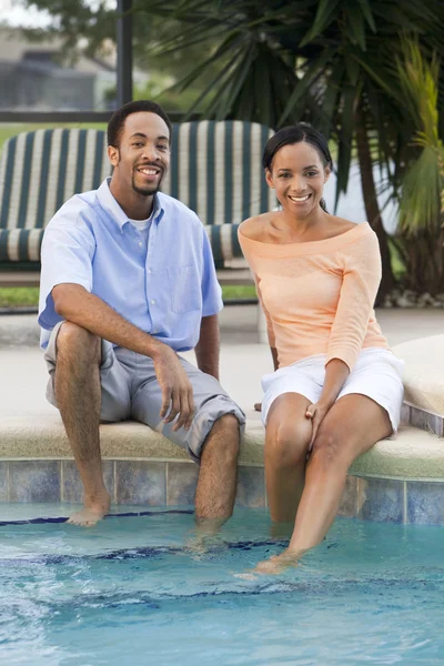 Feliz pareja afroamericana sentada con los pies en la piscina — Foto de Stock