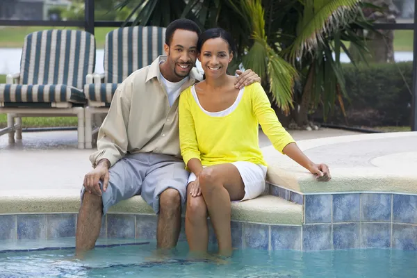 Gelukkig Afrikaanse Amerikaanse echtpaar zitten buiten naast zwemmen p — Stockfoto