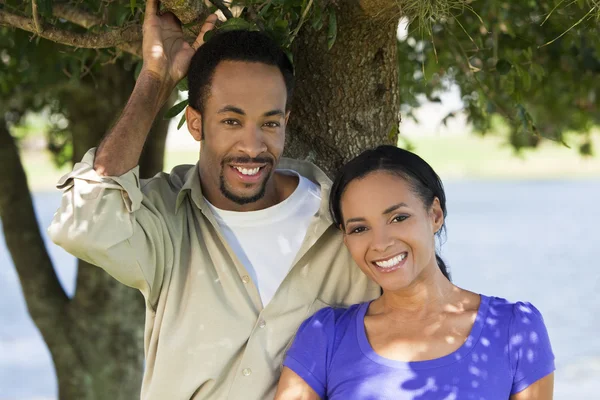 Feliz pareja afroamericana romántica sonriendo bajo un árbol — Foto de Stock