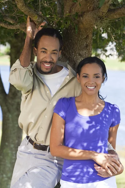 Felice coppia afroamericana tenendo le mani sotto un albero — Foto Stock