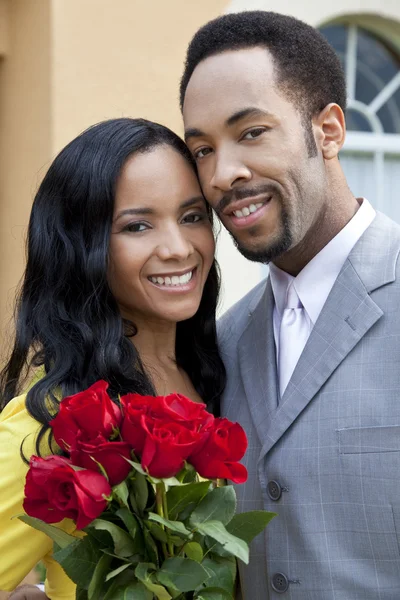 Casal afro-americano romântico com um monte de rosas — Fotografia de Stock
