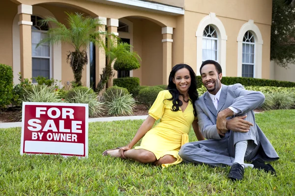 Happy African American Couple Beside House for Sale Sign — стоковое фото