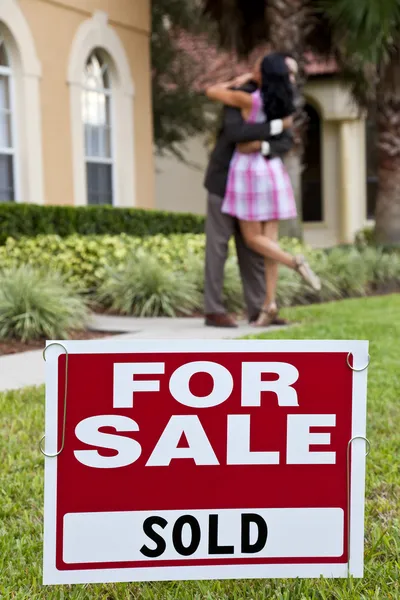 Афроамериканская пара празднует покупку дома на продажу знак — стоковое фото