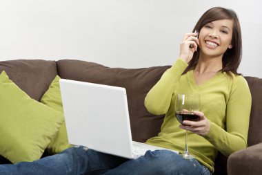 Asian Woman Drinking Wine on her Cell Phone Using Laptop clipart