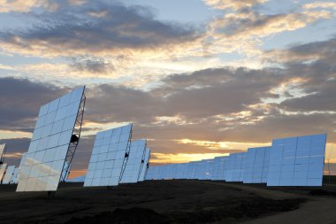 A Field of Green Energy Solar Mirror Panels at Sunset clipart