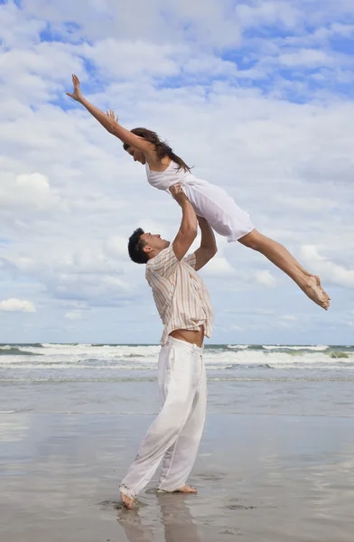 Homem e mulher yong casal, pulando em celebração na praia — Fotografia de Stock
