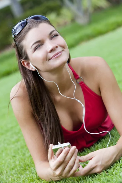 Hermosa morena mujer acostada escuchando MP3 Player —  Fotos de Stock