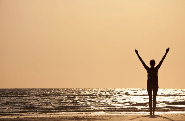Επιτυχημένη γυναίκα χέρια υψωμένα στο ηλιοβασίλεμα στην παραλία — Φωτογραφία Αρχείου