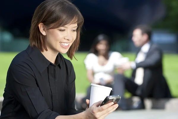 Schöne junge asiatische Frau SMS und Kaffee trinken — Stockfoto
