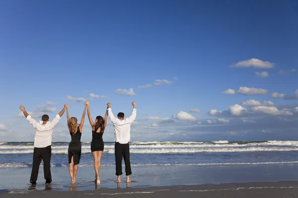 Cuatro jóvenes, dos parejas, brazos arriba celebrando en la playa —  Fotos de Stock