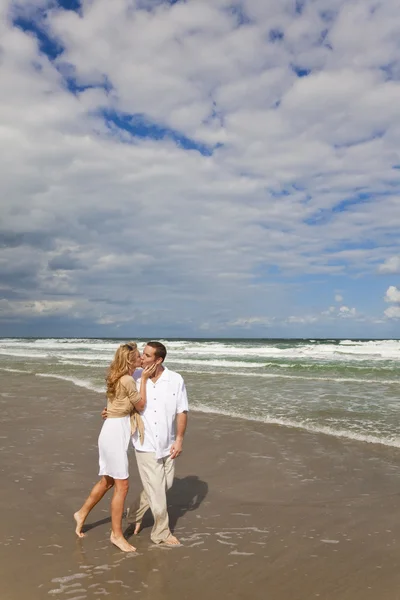 Homem e mulher casal caminhando e beijando em uma praia — Fotografia de Stock
