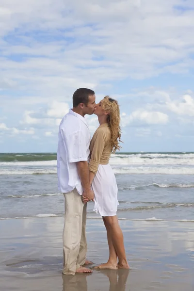 Hombre y mujer pareja sosteniendo manos besándose en una playa —  Fotos de Stock