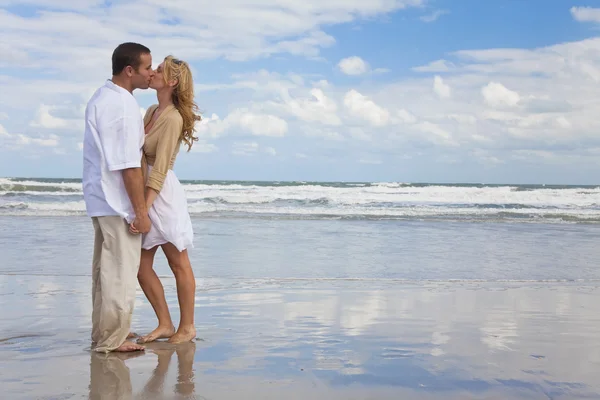 Hombre y mujer pareja sosteniendo manos besándose en una playa — Foto de Stock