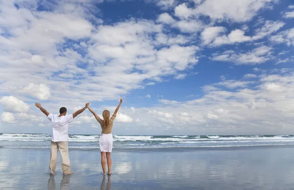 Coppia uomo e donna che festeggia le braccia sollevate su una spiaggia — Foto Stock