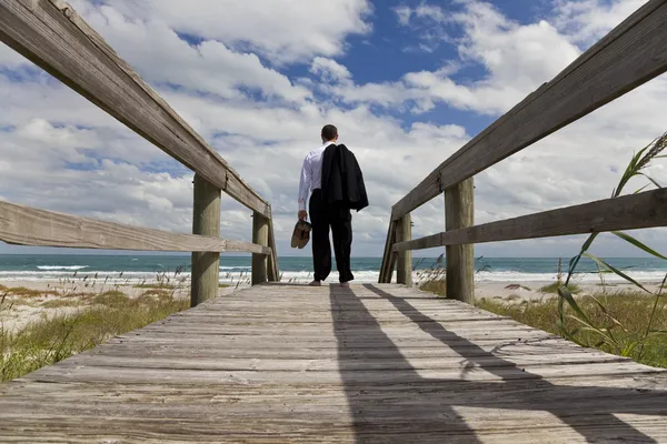 Uomo d'affari in piedi a piedi nudi guardando attraverso una spiaggia al mare — Foto Stock