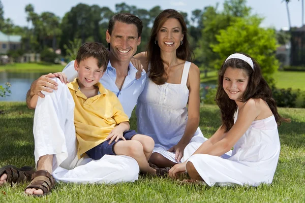 Família atraente sentado na grama fora na luz do sol — Fotografia de Stock
