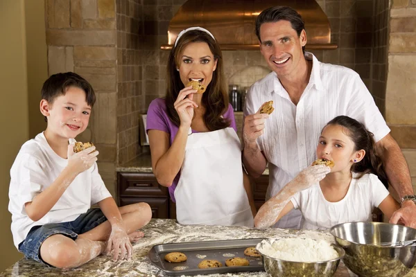 Attraente famiglia cottura e mangiare biscotti in una cucina — Foto Stock