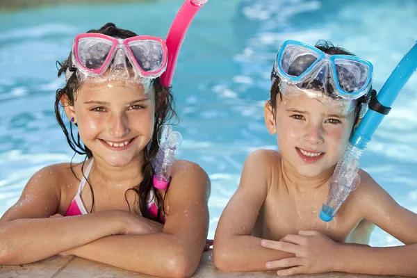 男孩和女孩在游泳池与护目镜和浮潜 图库图片