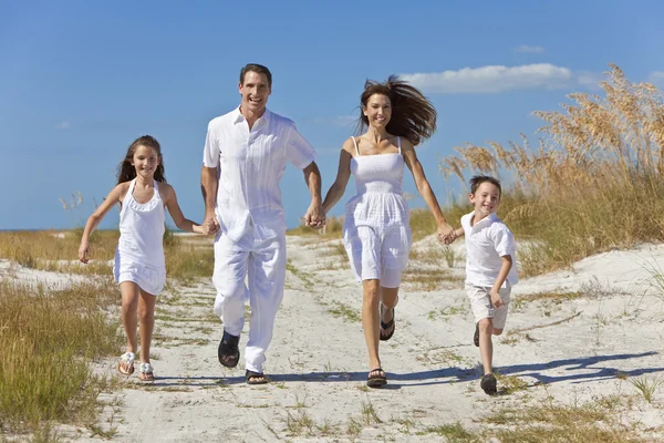 Mutter, Vater und Kinder laufen mit Spaß am Strand Stockbild
