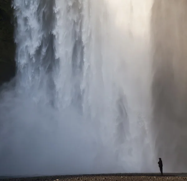 Mężczyzna w czarnym w stadninie wodospad — Zdjęcie stockowe