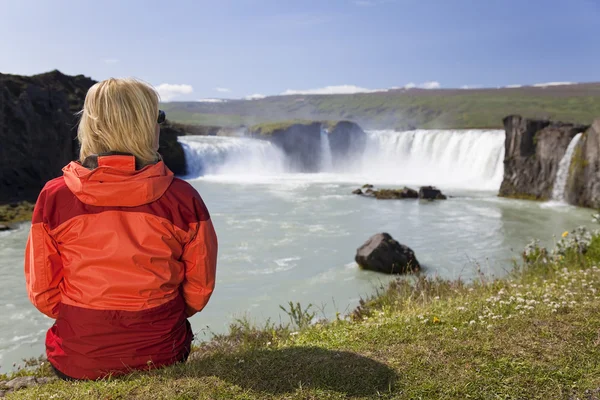 Женщина сидит у водопада Годафосс в Исландии — стоковое фото