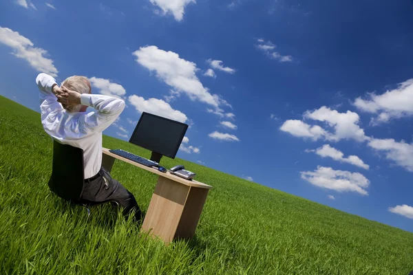 Uomo rilassante a ufficio scrivania in un campo verde — Foto Stock