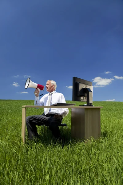 Homem conceito de negócios usando Megafone em um campo verde — Fotografia de Stock