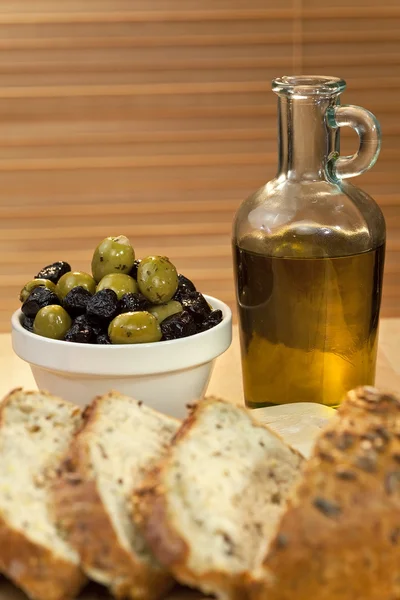 Оливковое масло, фаршированные зеленые и черные оливки и сельский хлеб — стоковое фото