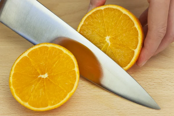 Szakács friss narancs szeletelés, éles konyhakéssel — Stock Fotó