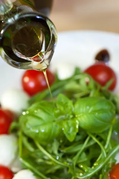 Оливковое масло Платье Наливая на свежий салат — стоковое фото
