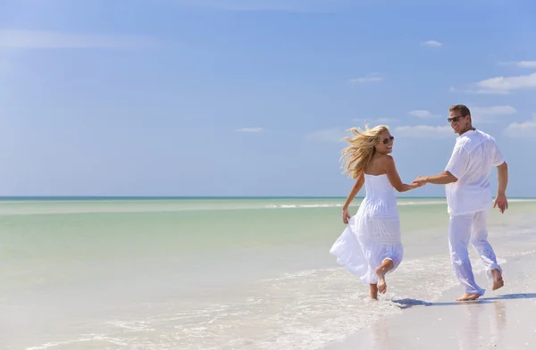 Glückliches junges Paar läuft Händchenhaltend an einem tropischen Strand — Stockfoto