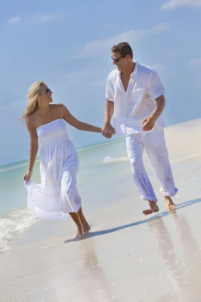 Feliz joven pareja corriendo sosteniendo las manos en una playa tropical —  Fotos de Stock