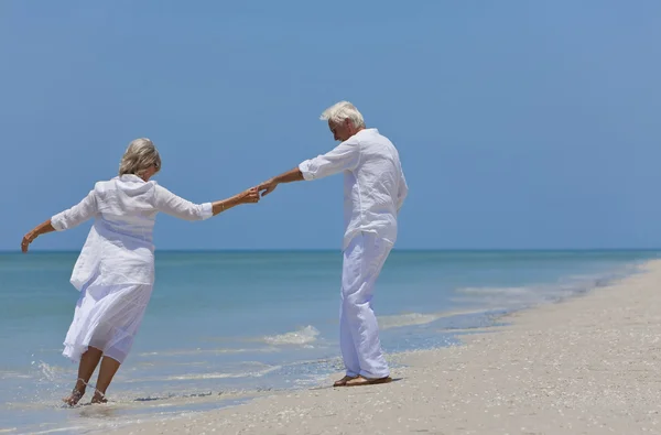 Heureux couple âgé dansant tenant la main sur une plage tropicale — Photo