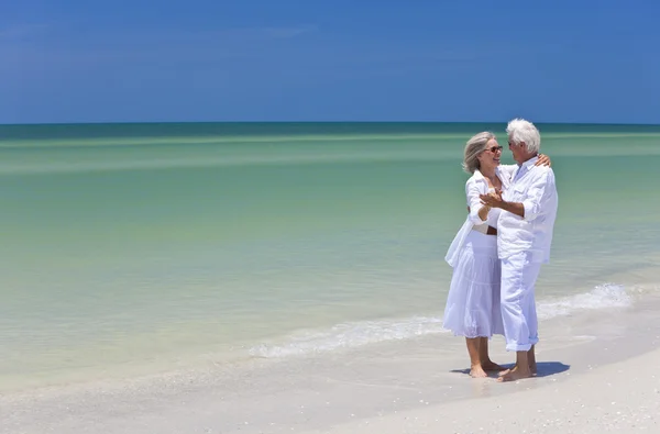 Gelukkige senior paar dansen bedrijf handen op tropisch strand — Stockfoto