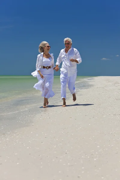 Felice coppia di anziani che corre tenendo le mani su una spiaggia tropicale — Foto Stock