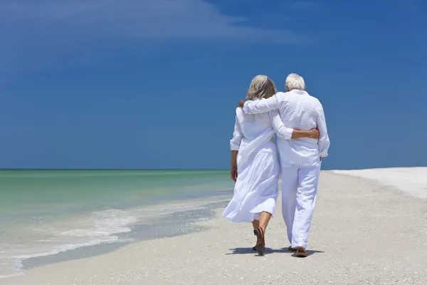 Задний вид пожилой пары, гуляющей в одиночестве по тропическому пляжу — стоковое фото
