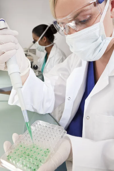 Kadın bilim adamıyla laborator pipet ve yeşil örnek tepsisinde — Stok fotoğraf
