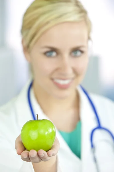 Mulher sorridente médico no hospital segurando maçã verde — Fotografia de Stock