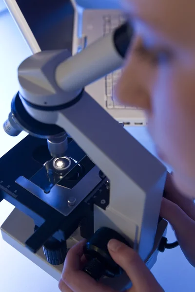 Женщина с помощью микроскопа и ноутбука в лаборатории — стоковое фото