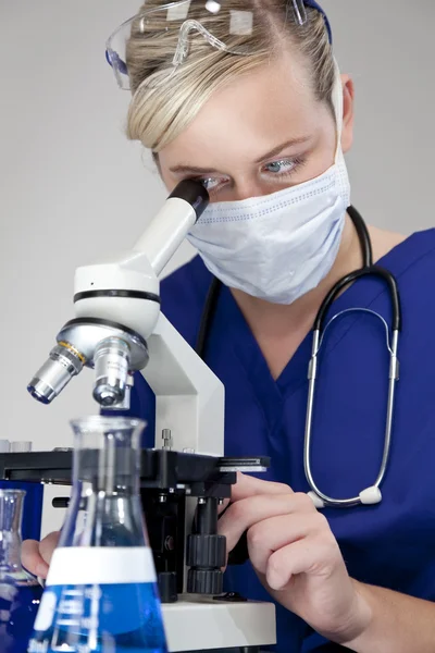 Piękne blond lekarz lub naukowiec przy użyciu mikroskopu w labora — Zdjęcie stockowe