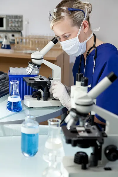 Γυναίκα γιατρός ή επιστήμονας χρησιμοποιώντας ένα μικροσκόπιο στο εργαστήριο — Φωτογραφία Αρχείου