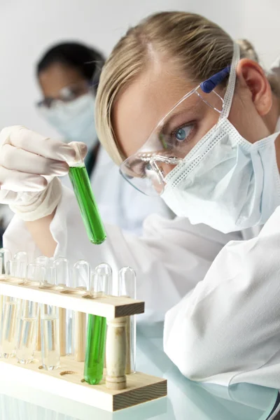 Squadra di ricerca scientifica femminile con soluzione verde in laboratorio — Foto Stock